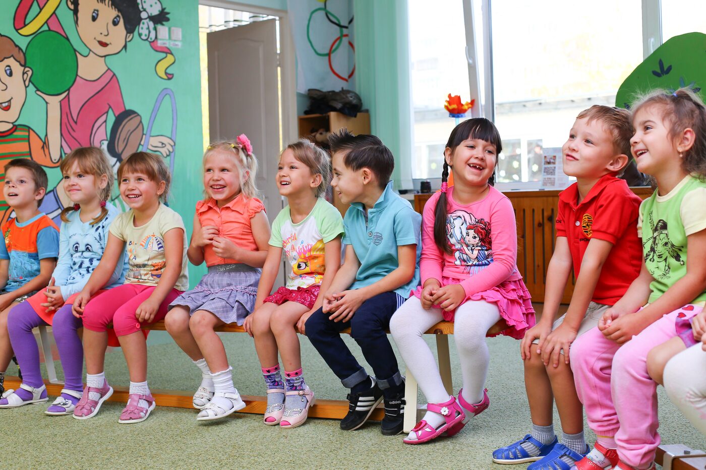 Kindergartenkinder sitzen fröhlich nebeneinander auf einer Bank