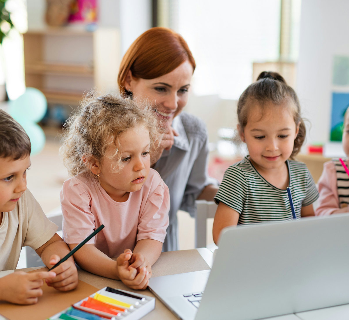 Kinder arbeiten mit ihrer Lehrerin am Laptop