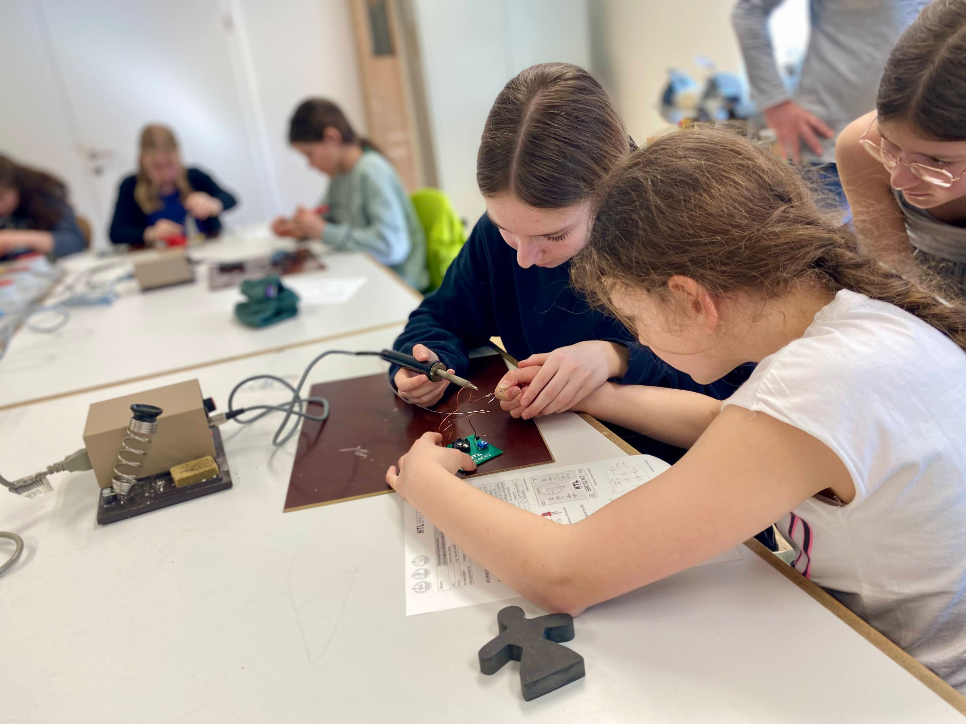 Zwei Mädchen löten elektronische Bauteile auf eine Platine