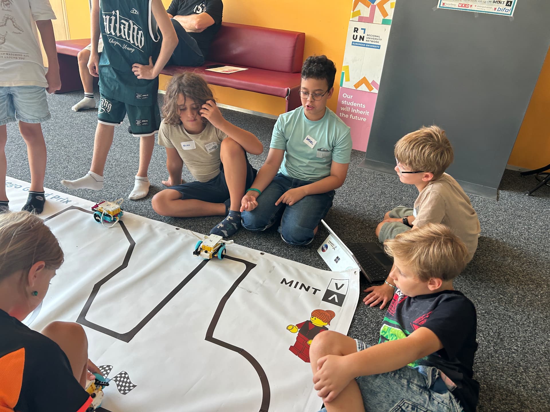 Kinder lassen Roboter über eine MINT-V-Matte fahren