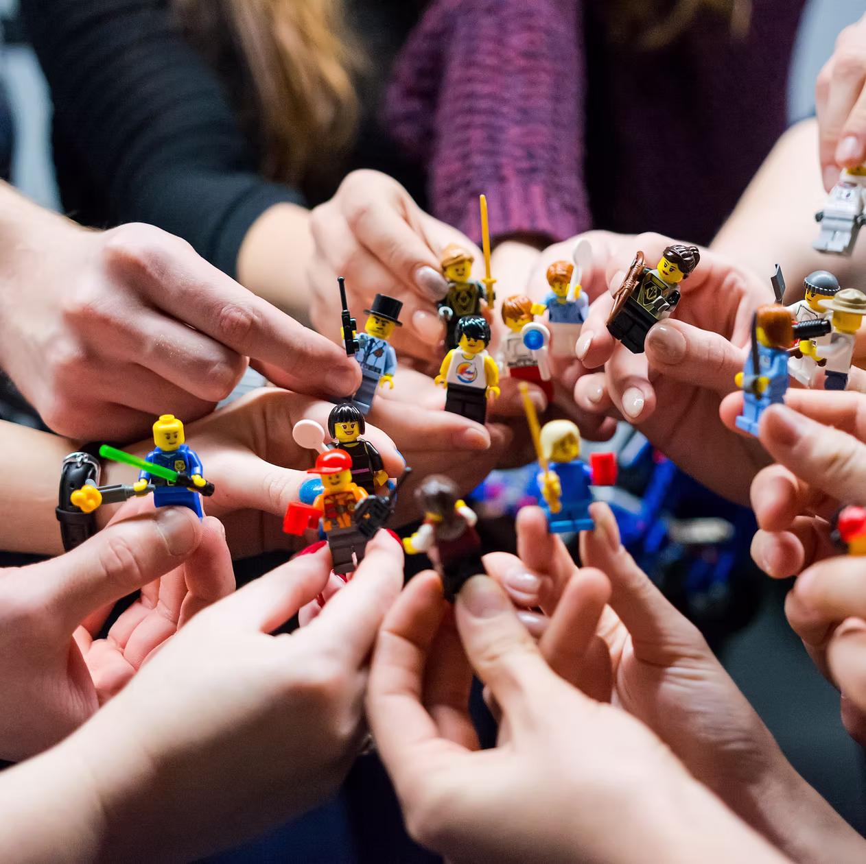Viele Hände halten Lego-Figuren