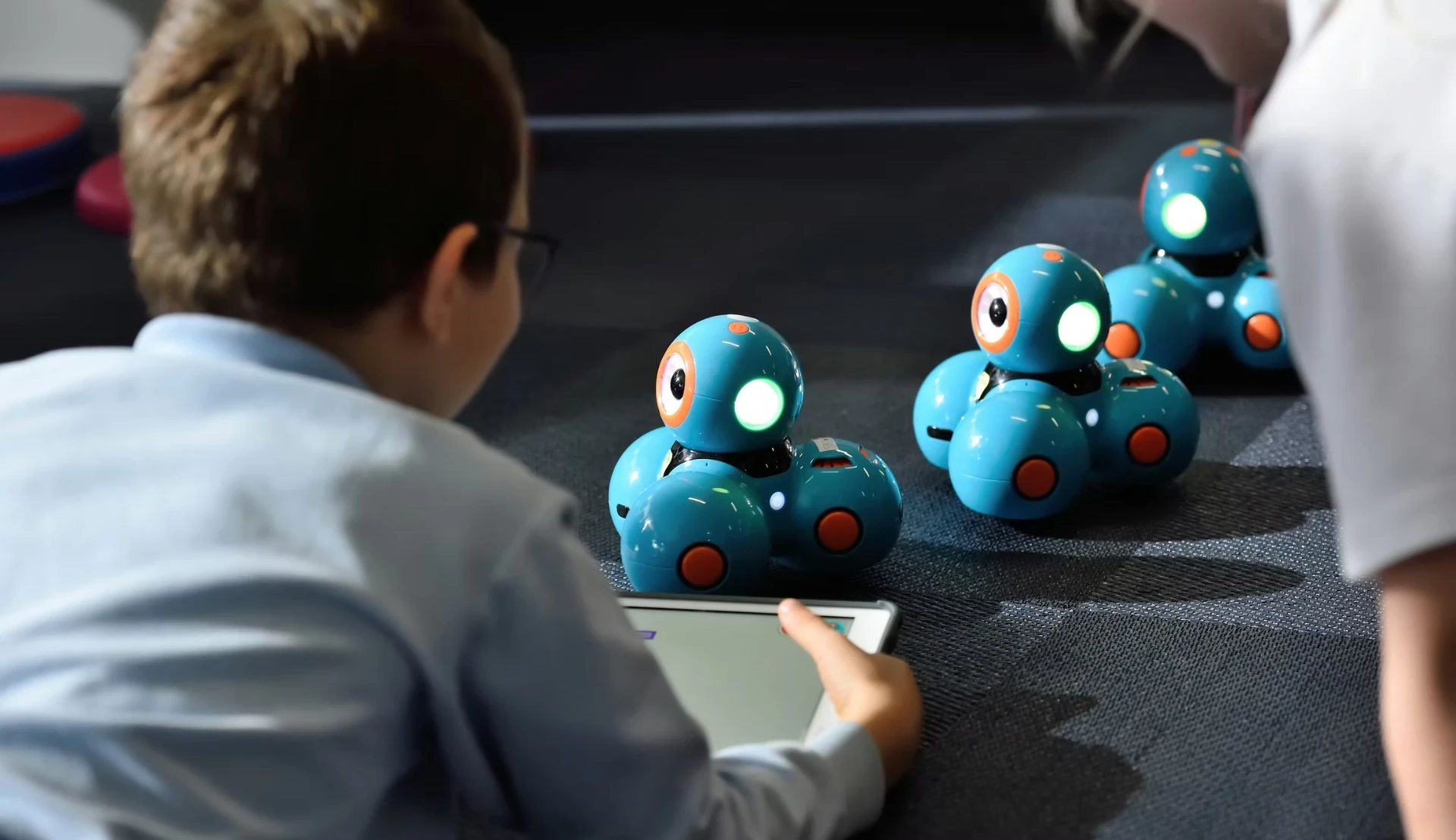 Kind programmiert Lernroboter mit einem Tablet