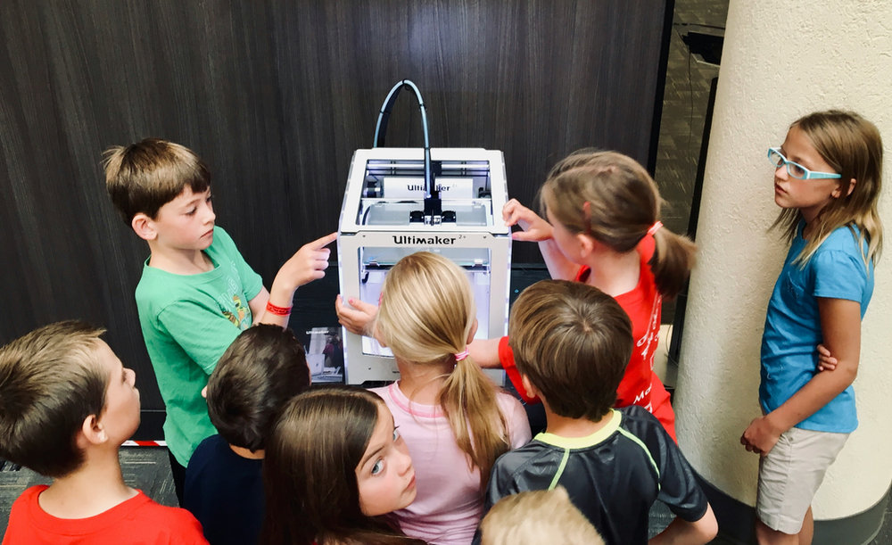 Kinder schauen gemeinsam einem 3D-Drucker zu