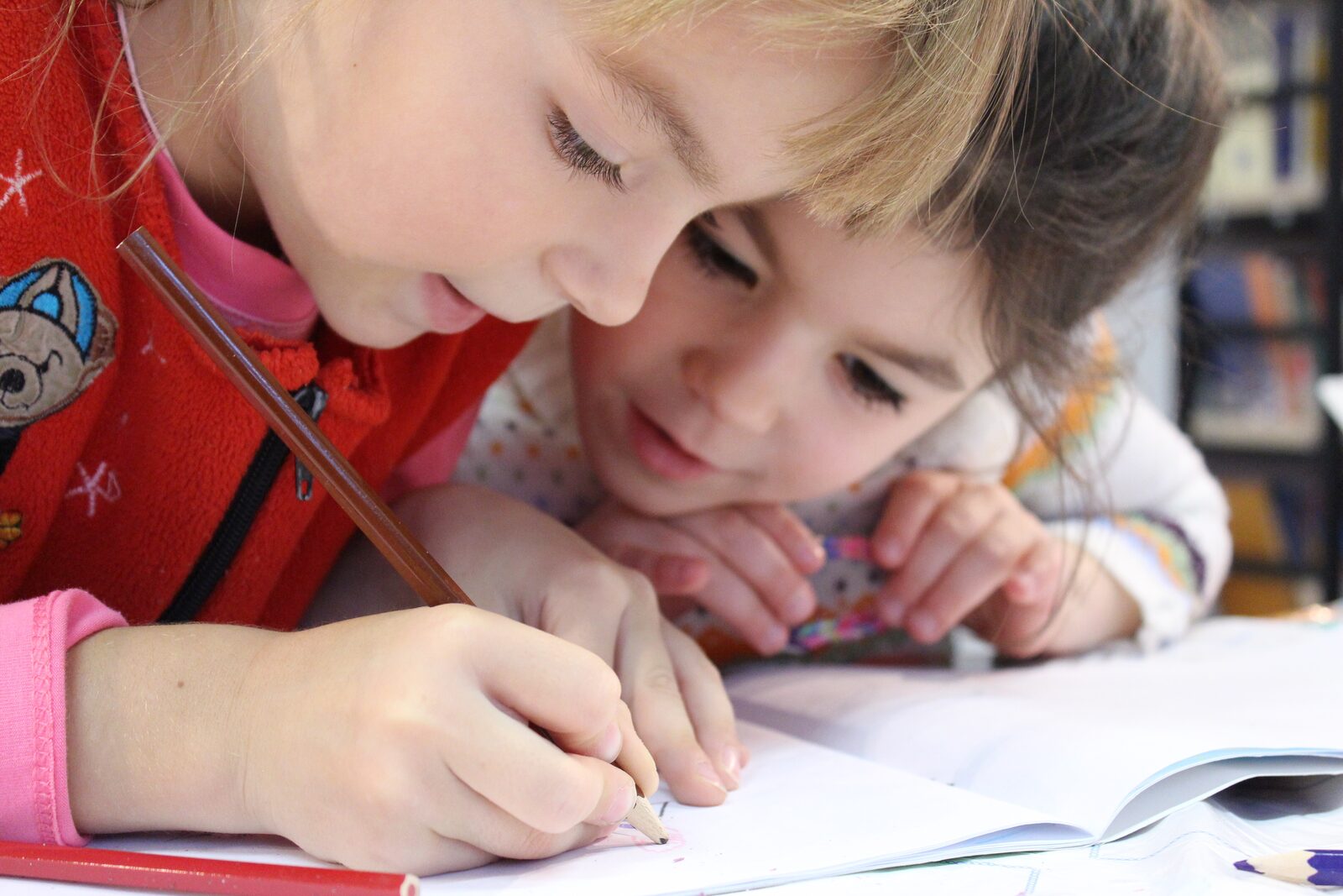 Zwei Kinder schreiben und zeichnen gemeinsam in ein Heft