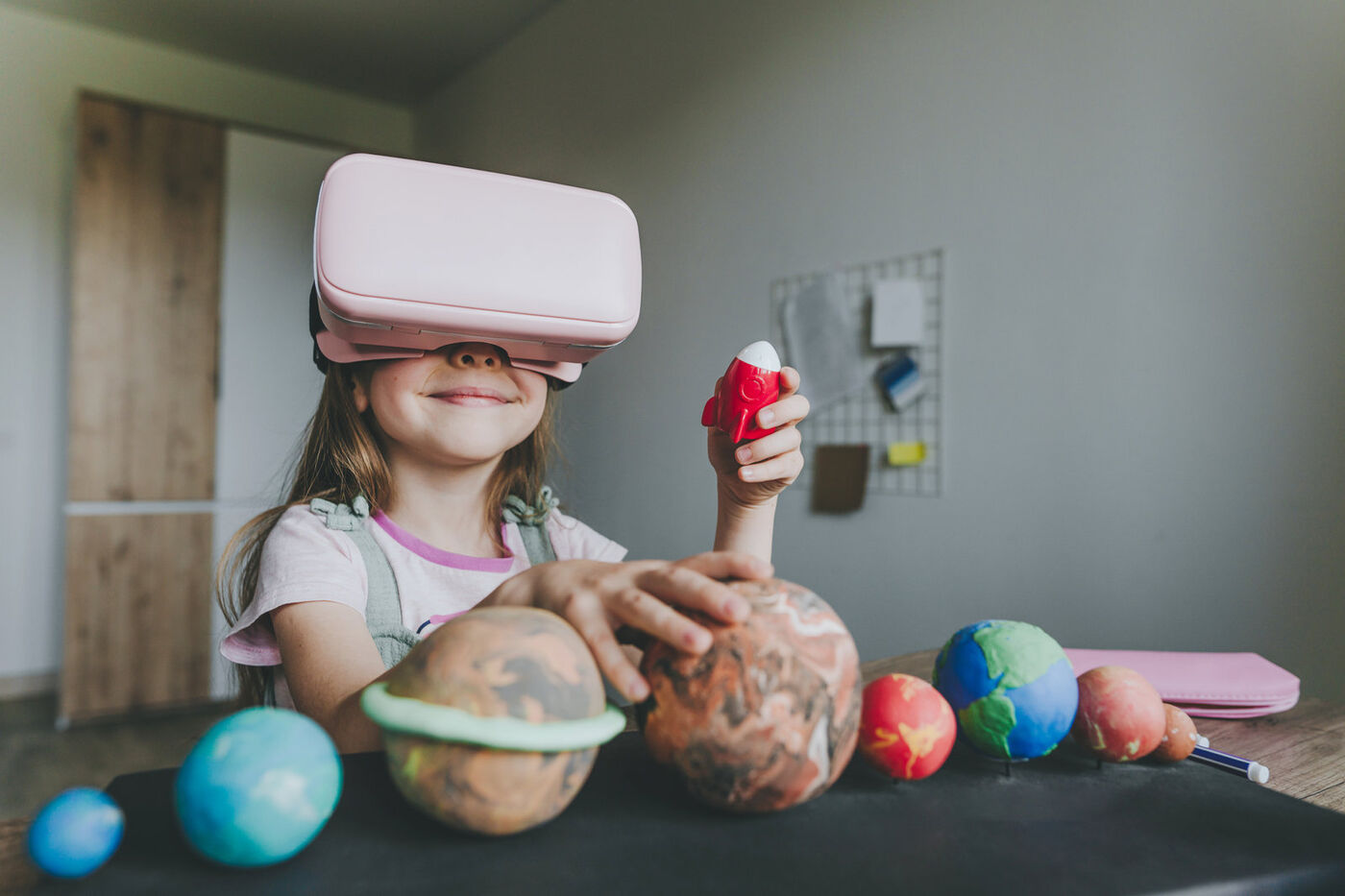 Mädchen mit VR-Brille und Planetenmodellen